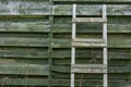 Weathered wooden ladder leaning on wooden slats