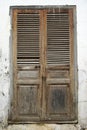 Weathered wooden louvered door set in an ancient crumbling stucco wall