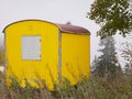 Weathered yellow shed in foggy forest.