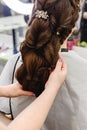 Weave, braid tail hairstyle. Hairdresser making hairstyle to brown hair woman with long hair in beauty salon. Professional Royalty Free Stock Photo