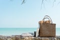 Weaving bag or Basket with towel, bottle of sun screen or sunscreen lotion, swimming robe and book next to a sea beach, summer Royalty Free Stock Photo