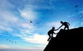 Teamwork climbing silhouettes of two people helping climbing by hand