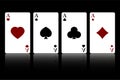 Set of four suits of playing cards with aces isolated on a black background with reflection Royalty Free Stock Photo