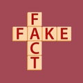 Fact or fake text cubes in the form of a crossword puzzle on a burgundy background. Royalty Free Stock Photo