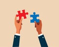 Two hands dressed in business attire are poised to connect two puzzle pieces, problem-solving, or the coming together of ideas.