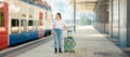 Web banner of travel. Young woman holding her luggage and waiting departure. Train station is in background. Concept of Royalty Free Stock Photo