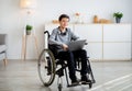 Web-based education for disabled pupils. Cheerful teen boy in wheelchair using laptop for online studies at home Royalty Free Stock Photo