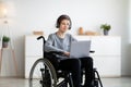 Web-based education for disabled students. Happy teen boy in wheelchair communicating online with tutor on laptop Royalty Free Stock Photo