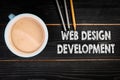 Web Design Development. Coffee mug and colored pencils on a black textured wooden background Royalty Free Stock Photo