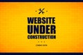 Website under construction sign on a brick wall.