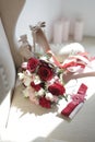 A bride`s bouquet of red and pink roses, women`s shoes, a garter of the bride Royalty Free Stock Photo