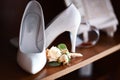 Wedding accessories bouquet beige flowers for groom and white shoes on heels, dark wooden background, morning of the bride