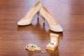 Wedding accessories. White shoes of the bride, Jewelry and a pair of gold wedding rings on a brown background