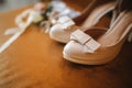 Wedding accessory bride. Stylish beige shoes, buttonhole and garter on wooden background. Royalty Free Stock Photo