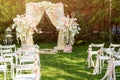 Wedding arch decorated with cloth and flowers outdoors. Beautiful wedding set up. Wedding ceremony on green lawn in the