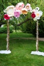 The wedding arch decorated with handmade flowers on the green lawn