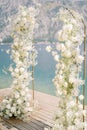 Wedding arch decorated with white flowers stands on the pier. Side view Royalty Free Stock Photo