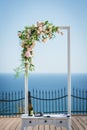 Wedding arch decorated with white and pink roses and green leaves. Outdoor wedding ceremony
