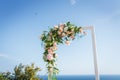 Wedding arch decorated with white and pink roses and green leaves. Outdoor wedding ceremony