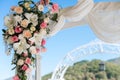 Wedding arch detail - pink and white flowers arranged with an ethereal veil against blue sky