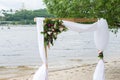 A wedding arch with greenery, peonies, and white material.