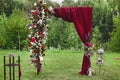 Wedding arch with vinous curtain and fresh flowers outdoors - wedding decoration