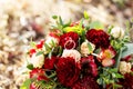 Wedding background bouquet and rings.The bride`s bouquet of red and pink flowers and greenery, with a ribbon of color Marsala. Royalty Free Stock Photo