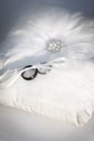 Wedding bands tied to a white pillow made with feathers and pearls Royalty Free Stock Photo