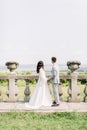 Wedding beautiful Chinese couple in the sunny day in ancient castle, posing and holding hands near the old railings Royalty Free Stock Photo