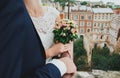 Wedding blonde couple is kissing in the ancient cafe on the roof. Groom and bride in lace satin dress are hugging over the