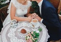 Wedding blonde couple is kissing in vintage cafe outdoors. Groom and bride in lace satin dress are holding hands and drinking Royalty Free Stock Photo