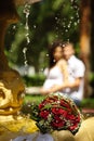 The Wedding Bouquet Of The Bride Of Red Roses Lies In An Old Fountain Under Splashes And Drops Of Water. Royalty Free Stock Photo