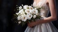 The bride in a white wedding dress holds a wedding bouquet. The bouquet consists of white