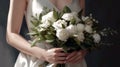 The bride in a white wedding dress holds a wedding bouquet. The bouquet consists of white