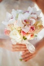 Wedding bouquet in bride's hands with orchids anf roses