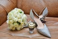 Wedding bouquet, bride shoes and perfume on a leather chair. Royalty Free Stock Photo