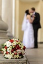 Wedding bouquet of flowers on background of bride and groom kissing