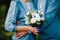 Wedding bouquet flowers from bush roses, eustoma in hands, on the background stylish brides woman wearing embroidered dress and