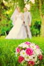 Wedding bouquet on green grass and verry blurred young wedding c Royalty Free Stock Photo