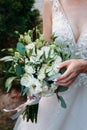 Wedding bouquet in the hands of a beautiful bride of white and milk roses in a dress