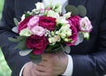 Wedding bouquet in hands at the groom. Flowers close-up