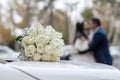 Wedding bouquet on the hood of the car on the background of the bride and groom Royalty Free Stock Photo