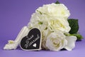 Wedding bouquet with Just Married heart sign against purple background.