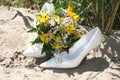 Wedding bouquet lies on the bride's shoes on the sand