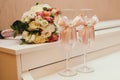 A wedding bouquet lies next to glasses decorated with pink ribbons Royalty Free Stock Photo