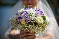 A wedding bouquet of light roses in the hands of the bride. Beige and pink flowers.