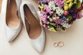 Wedding bouquet near the bride`s shoes and wedding rings Royalty Free Stock Photo