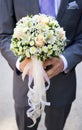 Wedding bouquet of pale pink and yellow flowers and ribbons in hands of groom