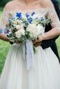 Wedding bouquet of peonies, blue flowers and greenery in bride`s hands Royalty Free Stock Photo