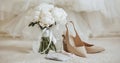 Wedding bouquet of peonies flowers in a vase stands on the bed of the newlyweds with invitations and shoes on the background of